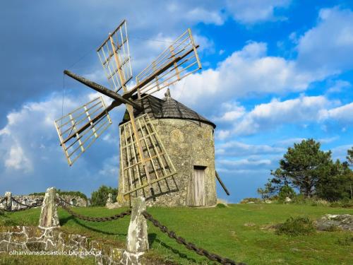 a stone windmill in a field with a blue sky at Casa da Varanda in Carreço