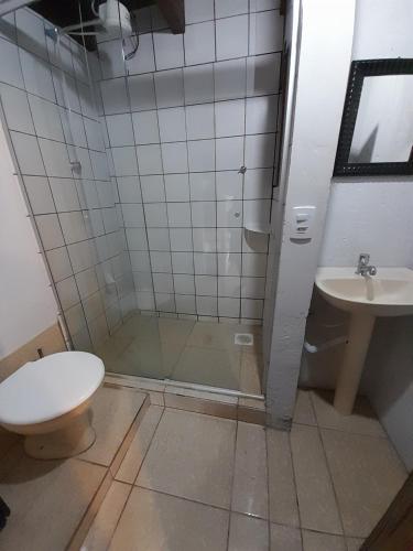 a bathroom with a shower and a toilet and a sink at Pousada das Palmeiras in Garopaba