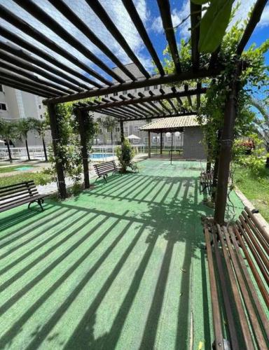 a wooden pergola with two benches in a park at Apartamento próximo ao aeroporto in Fortaleza