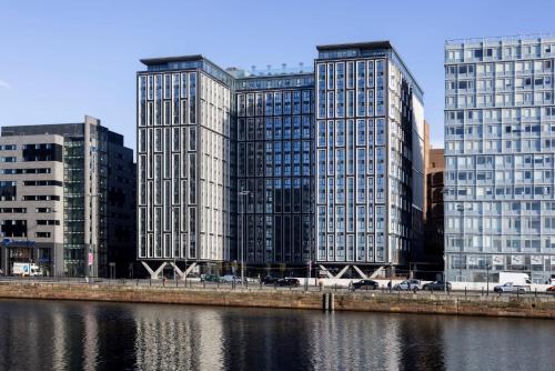 three tall buildings in a city next to a river at Copper House in Liverpool in Liverpool