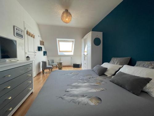 a bedroom with a large bed with a blue wall at La Maison Sarthoise - 24H Du Mans - 4 pers in Saint-Saturnin