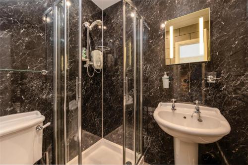 a bathroom with a glass shower and a sink at The Tall House - Sleeps 16 in Keswick