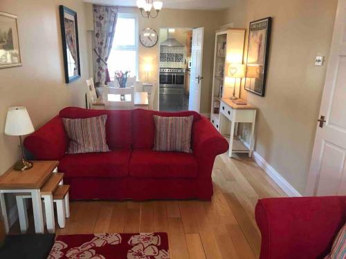 uma sala de estar com um sofá vermelho e uma cozinha em Downshire Cottage: Cosy home in Holywood Centre em Holywood