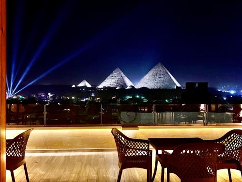 uma mesa e cadeiras numa varanda com pirâmides em Celia Pyramids View inn no Cairo