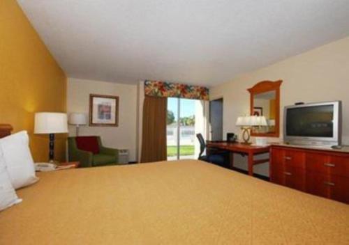 a hotel room with a bed and a desk and a television at Quality Inn Downtown Stuart in Stuart