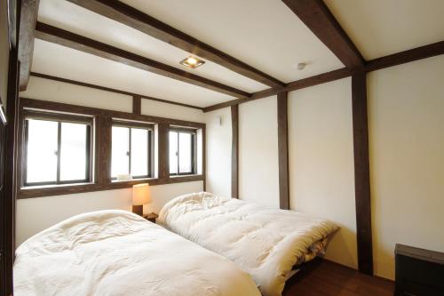 a bedroom with a bed and two windows at SOY in Takayama