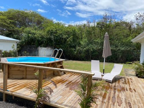 Eine Terrasse mit Pool, zwei Stühlen und einem Sonnenschirm in der Unterkunft Kaz’Ary in Sainte-Anne