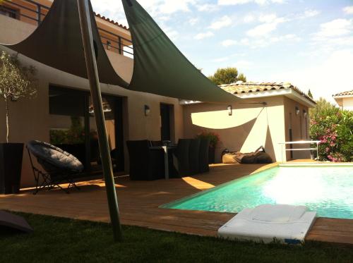a swimming pool with a green umbrella over it at Le Hameau de la Crique de l'Anglaise in Bandol