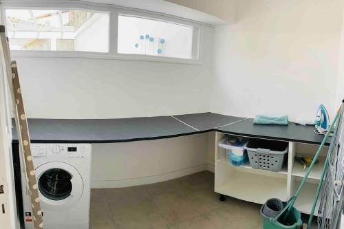 una lavanderia con bancone e lavatrice di Maison centre ville confortable a Marmande
