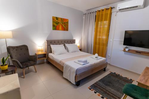 a bedroom with a bed and a tv and a chair at Lion's Cave suite No 1. in Kalamata