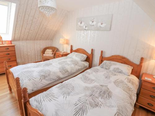 een slaapkamer met 2 bedden en een kroonluchter bij Corncrake Cottage SU in Pollachar