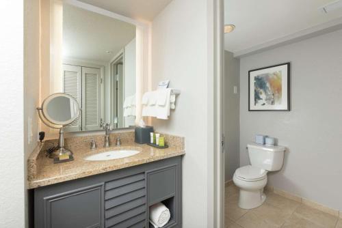 a bathroom with a sink and a toilet and a mirror at Hilton Melbourne Beach Oceanfront in Melbourne