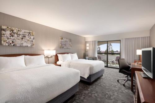 a hotel room with two beds and a flat screen tv at Courtyard by Marriott San Jose South/Morgan Hill in Morgan Hill