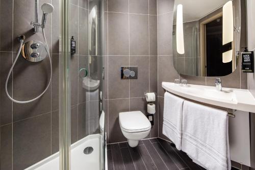 La salle de bains est pourvue d'une douche, de toilettes et d'un lavabo. dans l'établissement ibis London Canning Town, à Londres
