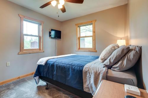 a bedroom with a bed and two windows at Pet-Friendly Iron River Cabin with Fire Pit! in Iron River