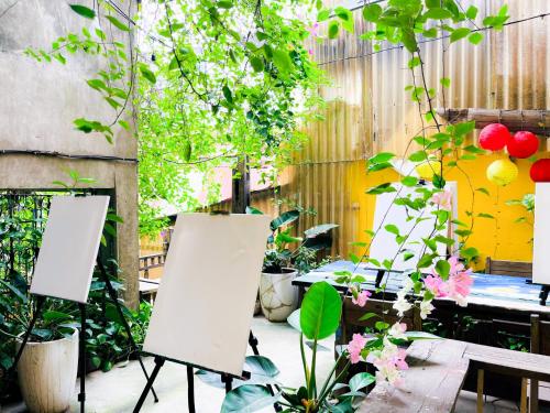 two easels are standing in a garden with plants at Chủ Nhật Cafe & Homestay - 12 ngõ 41 Đường Láng - Cơ sở 1 in Hanoi