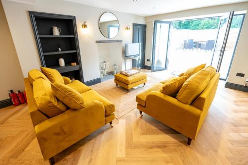 a living room with two yellow couches and a mirror at Siabod - Snowdonia, North Wales in Bethesda