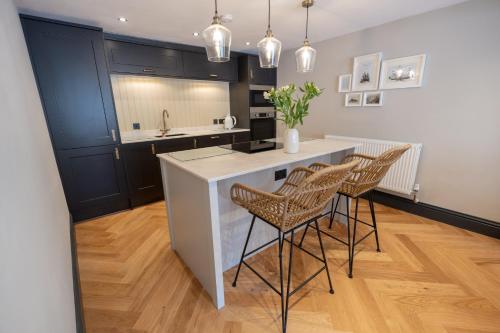 a kitchen with a white counter and some chairs at Siabod - Snowdonia, North Wales in Bethesda