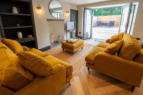a living room with two yellow couches and a television at Siabod - Snowdonia, North Wales in Bethesda