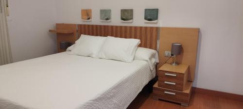 Schlafzimmer mit einem Bett mit einem Kopfteil aus Holz und einem Nachttisch in der Unterkunft Apartamento Torres19 in Sevilla
