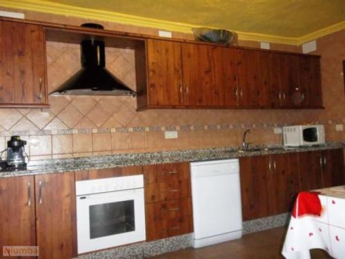 La cuisine est équipée de placards en bois et d'un four avec plaques de cuisson. dans l'établissement El Aguacate, à Lanjarón