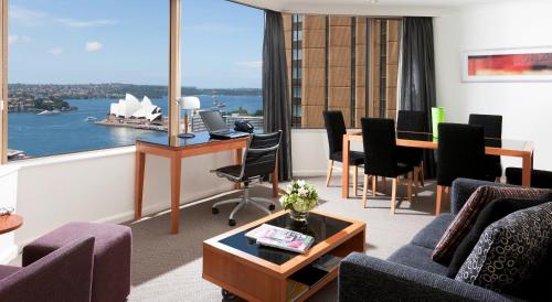 a living room with a table and a large window at The Sebel Quay West Suites Sydney in Sydney