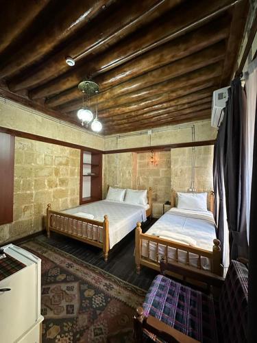 1 dormitorio con 2 camas y techo de madera en Hayadlı Konak Butik Otel en Gaziantep