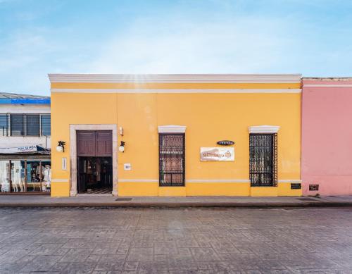 a yellow building with three windows on a street at Hotel Santiago in Mérida