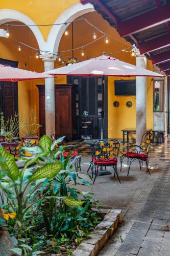 a patio with chairs and tables and an umbrella at Hotel Santiago in Mérida