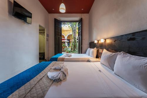 a hotel room with two beds and a window at Hotel Santiago in Mérida