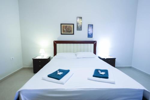 een slaapkamer met een wit bed en 2 handdoeken bij Royal House in Elbasan