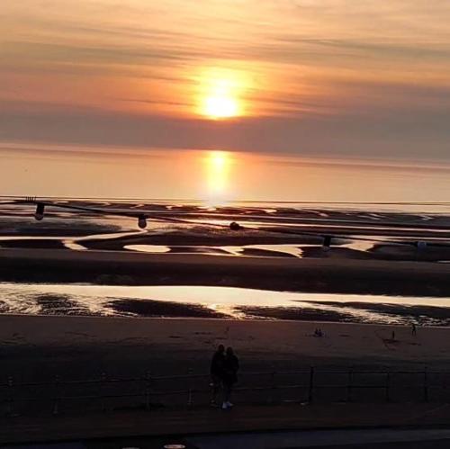 two people walking on the beach at sunset at The Rutland in Blackpool