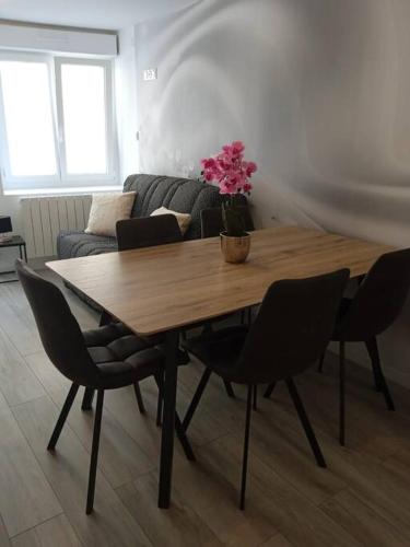 une table en bois avec des chaises et un vase avec des fleurs. dans l'établissement Nuit étoilée - Dormir Comme A La Maison, à Saint-Julien-de-Vouvantes