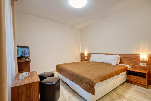um quarto de hotel com uma cama e uma televisão em Къща за гости Relax em Hisarja