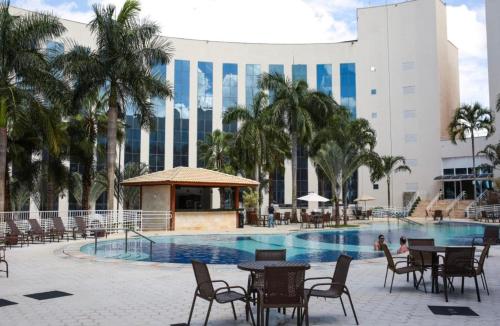 une piscine avec des tables et des chaises en face d'un bâtiment dans l'établissement Flat dentro Parque do Peão de Barretos, à Barretos