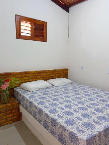 a bedroom with a bed with a blue comforter and a window at Chalé Duplo in Pacoti