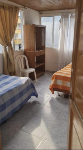 1 dormitorio con 2 camas, vestidor y ventana en hotel amazonico, en Mocoa
