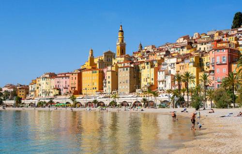 a group of people on a beach in front of a city at Patio de la pietonne in Menton