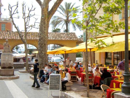 a group of people sitting at tables with umbrellas at Patio de la pietonne in Menton