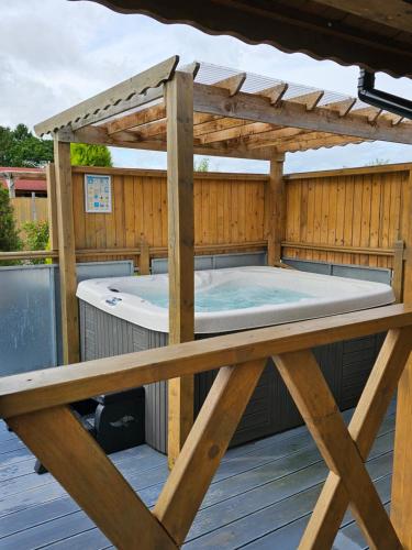 a hot tub on a deck with a wooden pergola at The Windsor Lodge in Ellesmere