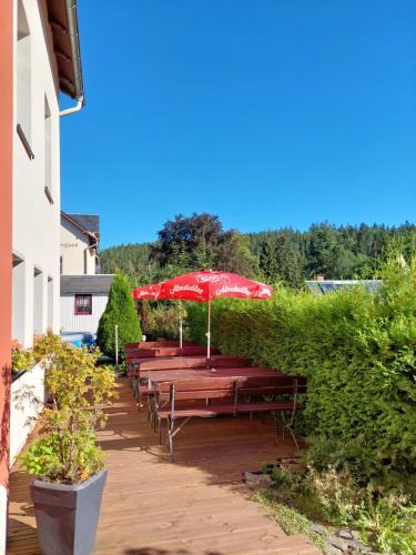 a row of tables with red umbrellas on a patio at Villa Helvetia in Bad Elster