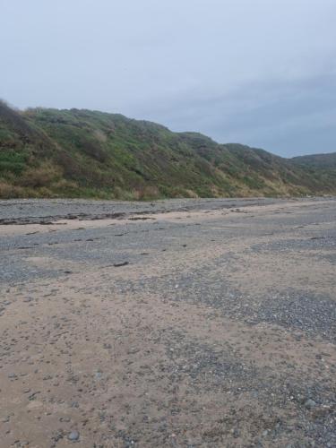 an empty beach with rocks and hills in the background at Serenity in Monreith
