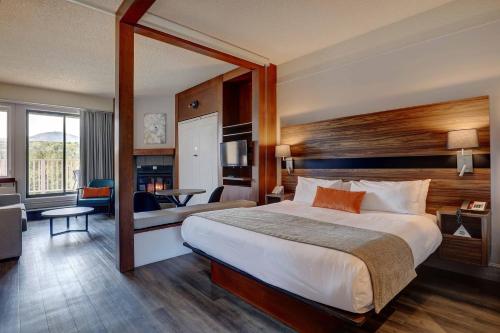 a hotel room with a large bed and a living room at Estrimont in Magog-Orford