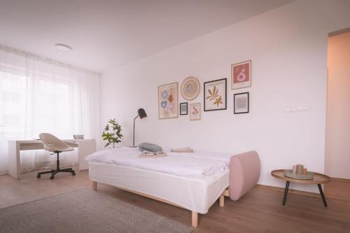 a white bedroom with a bed and a desk at Nový štýlový byt, blízko letiska in Bratislava