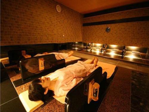 two people laying in beds in a room at Hotel Lexton Kagoshima in Kagoshima