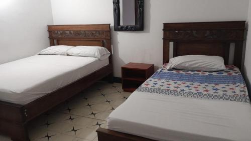 a bedroom with two beds and a mirror at HOTEL LA CORDIALIDAD in Barranquilla