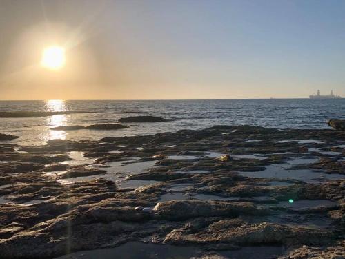 a beach with the sun setting over the water at Namibia Coastal Retreat in Walvis Bay