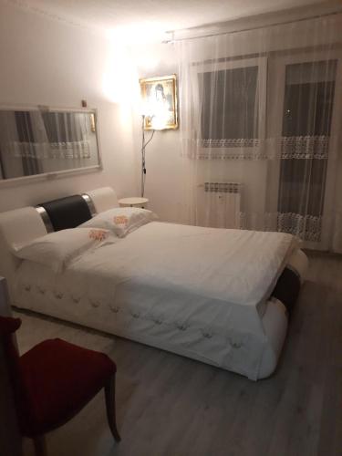 a bedroom with a large white bed in a room at Nada apartman in Vukovar