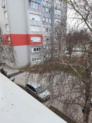 a car parked in front of a building in the snow at Nada apartman in Vukovar