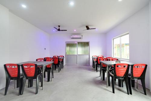 a conference room with tables and red chairs at Hotel O Mango Leaf Hotel & Restaurant in Baharampur